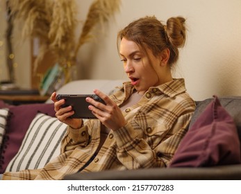 The girl enthusiastically and emotionally plays a video game on a portable game console. Fun pastime, recreation, relaxation, cyberspace, cybersport, online games with friends, competitions, battles.
