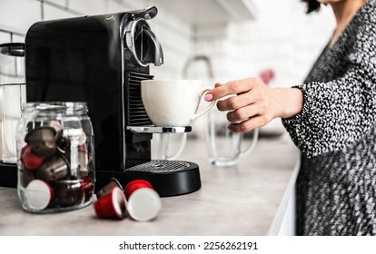 Girl with espresso cup prepared in capsule coffee machine at home. Woman making italian caffeine beverage - Shutterstock ID 2256262191