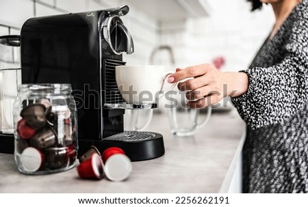 Girl with espresso cup prepared in capsule coffee machine at home. Woman making italian caffeine beverage