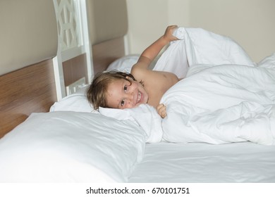 A girl of European appearance plays in bed for 4-5 years. She is sick and her face is covered with pimples. The kid is having fun.