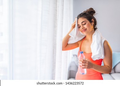 Girl Exercising At Home She Tired And She Has Sweat On Her Face. Side Profile View Photo Portrait Of Sexual Attractive Beautiful Glad Sportive Woman Holding Bottle In Hand Standing In White Room