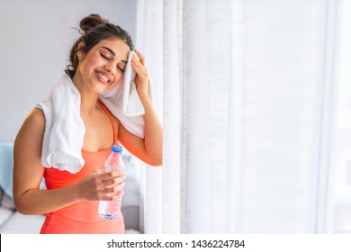 Girl Exercising At Home She Tired And She Has Sweat On Her Face. Side Profile View Photo Portrait Of Sexual Attractive Beautiful Glad Sportive Woman Holding Bottle In Hand Standing In White Room