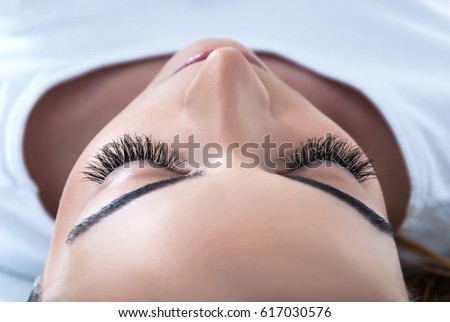 Girl with extended silk eyelashes lies in a beauty studio