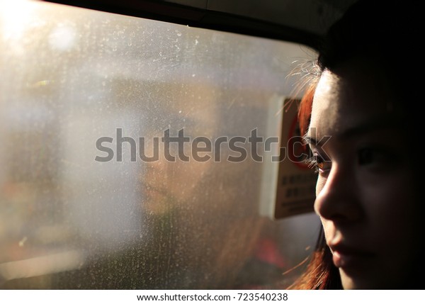 girl face watching out the train with the evening\
sun bright