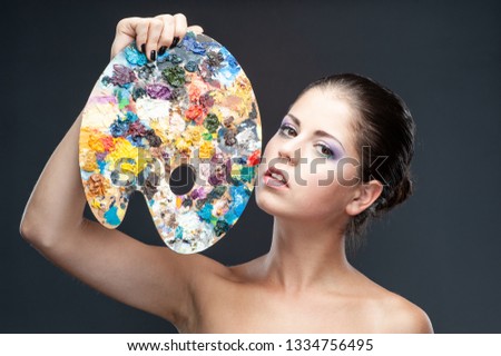Girl with fantasy make-up holds a palette for artists