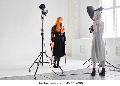 Girl Fashion Model And Photographer Are In The Studio On White Background