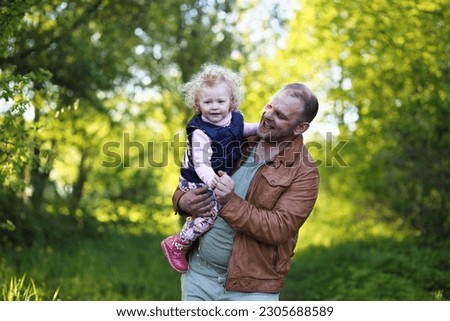 Girl with father in the park in the evening of a sunny day in the spring
