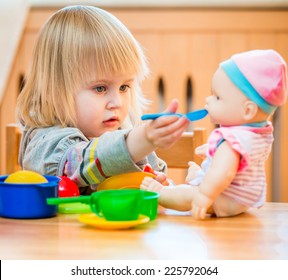 girl feeding a doll at home in the children's room