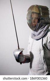A girl in a fencing suit with a sword in hand. Young female model practicing and exercising. Sports, healthy lifestyle.