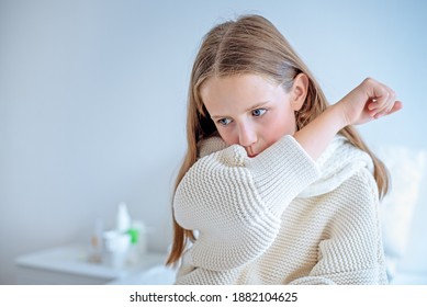 A girl with a fever sits on the bed and coughs. - Powered by Shutterstock