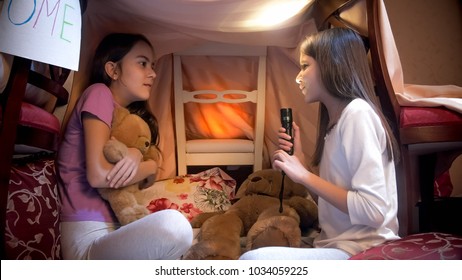 Girl With Flashlight Telling Scary Story To Her Friend