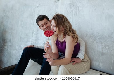 a girl flirts and plays with a guy, licking a multi-colored caramel candy. romantic relationship between a man and a woman.