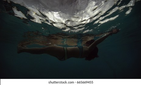 The Girl Floating Beneath The Water Surface. White Light Is Seen From Under The Water With The Girl's Body On The Top.