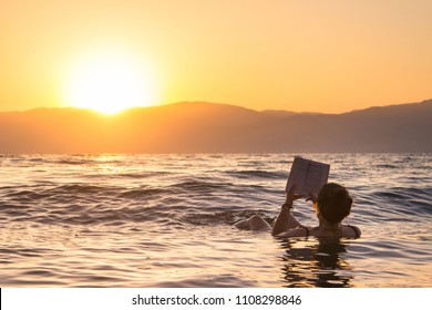 Girl Floating During Sunrise In The Dead Sea, Israel