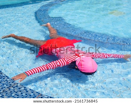 girl floating face down in the pool. girl diving in the swimming pool. Child face down starfish pose in swimming pool. swimming pool accident