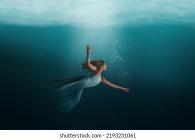 Girl floating in a surreal, dreamlike state under the deep waters of the ocean.  - Shutterstock ID 2193231061