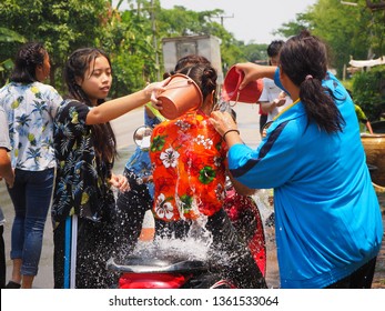 Girl in flower blossomed shirt is splashing water to her friend in Songkran festival in Thailand on April 13, 2018. Many boy and girl playing water at the street in their local.