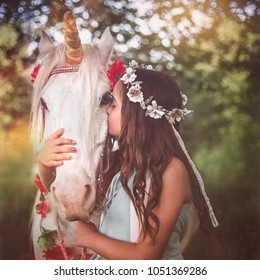 Girl with flower hair wreath hugging and kissing white unicorn. Dreams come true