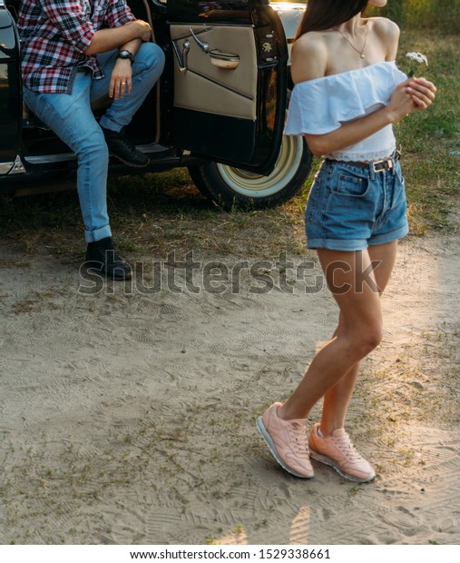 a girl with a\
flower and in a white blouse, a man in a plaid shirt is sitting on\
the back of the car\
seat,waiting