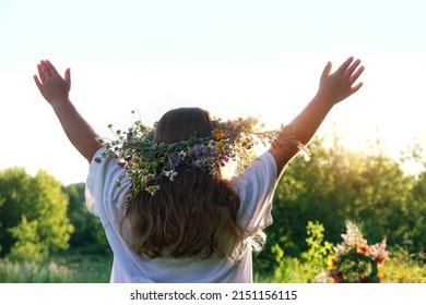 Girl in flower wreath on meadow, sunny natural green background. Floral crown, symbol of summer solstice. Slavic ceremony on Midsummer, wiccan Litha sabbat. pagan holiday Ivan Kupala - Shutterstock ID 2151156115