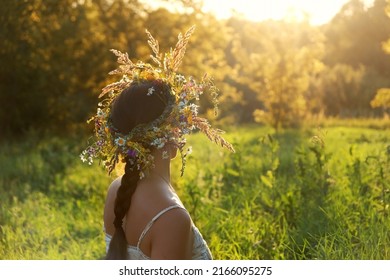 girl in flower wreath on meadow, sunny green natural background. Floral crown, symbol of summer solstice. Slavic ceremony on Midsummer, wiccan Litha sabbat. pagan holiday Ivan Kupala - Shutterstock ID 2166095275