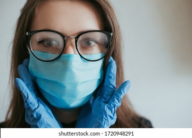 Girl In Foggy Glasses, In Blue Medical Mask And Gloves Wearing A Black Shirt On A Gray Background