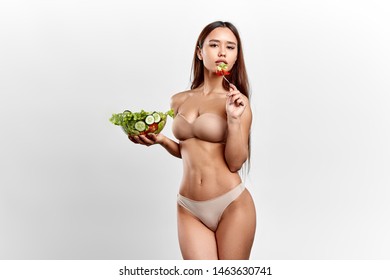 Girl Is Following Crash Diet, Tanned Slim Model Gets Pleasure From Eating Salad. Food Preference. Studio Shot