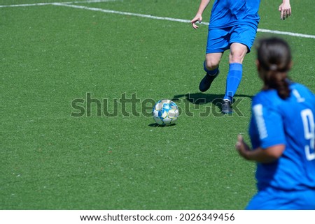 Girl football player attacking kicking soccer ball.