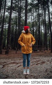 The Girl In The Forest Stands Against The Background Of Very Tall Trees. Travel In The Fall.