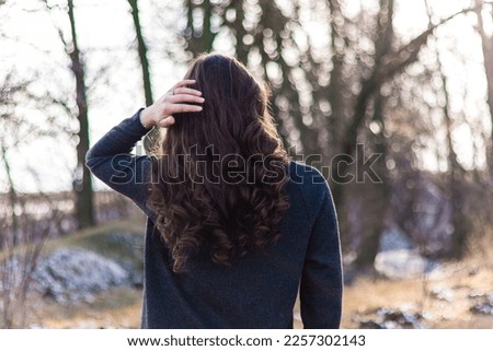 Girl in the forest.Woman with long curly hair.Photo in motion.The wind blows on her hair.Beautiful sunlight in the forest.Hair care.Beautiful hair.Walking in the forest.Bokeh and blur.Beautiful bright