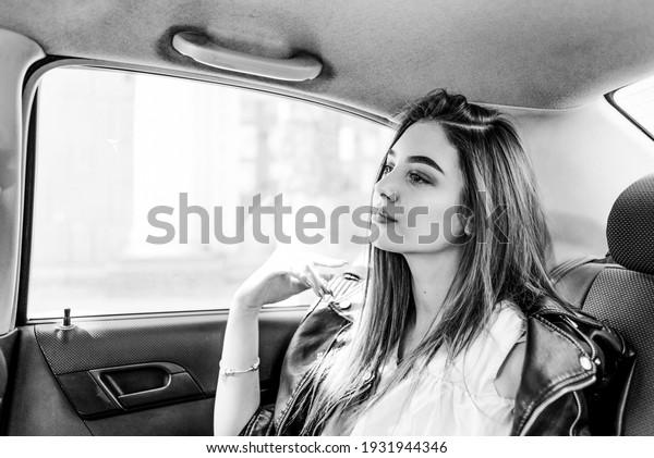 Girl in formal clothes rides in a\
car sitting in the back seat of the car. transport,\
fashion