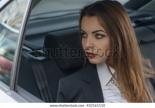Girl in\
formal clothes rides in a car sitting in the back seat of the car.\
Concept: transport, lifestyle,\
fashion