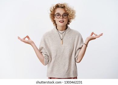 Girl Found Peace And Patience. Relaxed And Chill Woman Reaching Nirvana Looking Peaceful And Pleased At Camera Holding Hands Sideways In Lotus Pose With Zen Gesture, Meditating Over White Wall