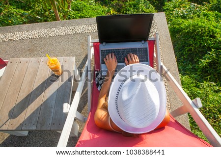 Girl freelance work typing on laptop black desktop with cold fresh cocktail juice outdoors sunny green trees. Traveling studying with a computer concept. Top above view on hat hands table