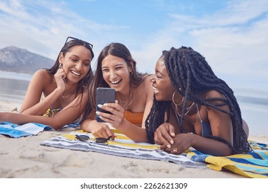 Girl friends, ocean fun and phone of a teenager laughing at funny meme by the sea in Miami. Travel, vacation and sunshine with happy students enjoying spring break with mobile app lying on sand - Powered by Shutterstock