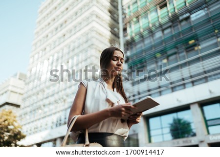 Girl frowns face while working online on the street. Business lady in a hurry