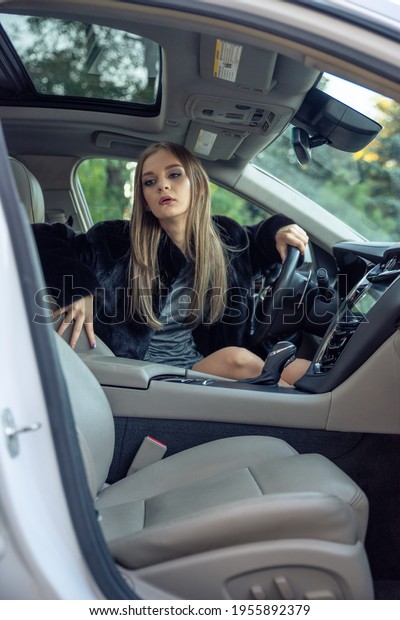 Girl in a fur coat in a car salon, chic image,\
expensive car, luxury