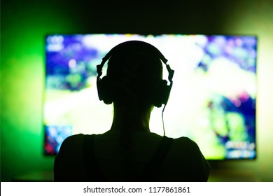 Girl Gamer In Headphones In The Dark On Tv Background. Ability To Use As Background. Silhouette