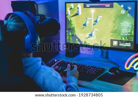 Girl gamer playing strategy game online using virtual reality headset - Soft focus on right hand