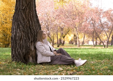 Girl gently hugs tree in forest clearing on sunny autumn day, symbolizing deep connection with nature and an exciting sense of calm in natural world. Lifestyle, Environmental Protection. - Powered by Shutterstock