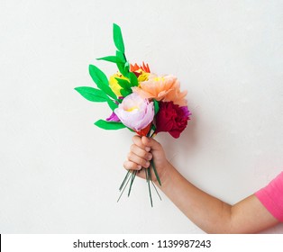 The Girl Gives A Bouquet Of Paper Flowers. Hands Hold A Gift. Birthday Party On March 8 Is Mother's Day. Child Creativity, A Favorite Hobby. Emotional Child. White Background.