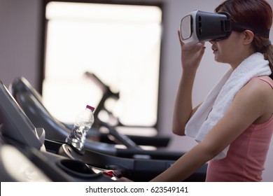 Girl in glasses of cyberspace running on treadmill.Active people doing exercises running on machine  spending time in virtual reality. - Powered by Shutterstock