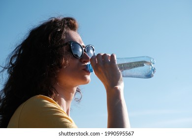 Girl With Glasses Drinks Water From A Bottle In Hot Weather.