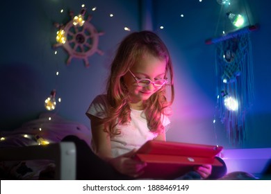 girl with glasses plays with tablet at night