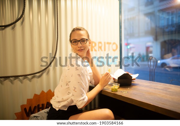 \
girl with glasses sits at tables in a fast\
food restaurant