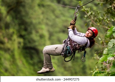 A girl glides on a zipline, her face filled with excitement, as she embarks on an adventurous journey through the lush canopy of Ecuador's Banos. - Powered by Shutterstock