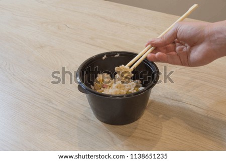 A girl is going to eat in a Chinese  food, they eating with chopsticks, close-up on hands and food. eating chinese beef and salad with chopsticks