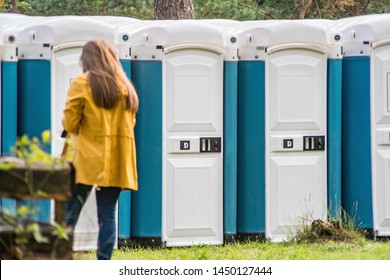 Girl going into portable toilet in a park.