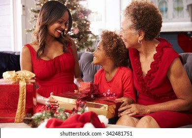 Girl With Grandmother And Mother Opening Christmas Gifts