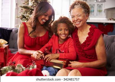 Girl With Grandmother And Mother Opening Christmas Gifts